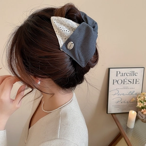 Détail de la pince à cheveux avec nœud en dentelle brodée sur un chignon bas élégant