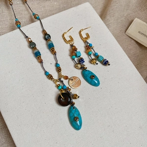 Dettaglio del set di gioielli vintage con perline turchesi e ciondoli dorati incisi