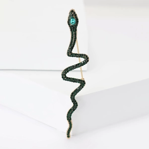 Macro shot of green rhinestone-encrusted snake brooch with gold base on a white stand