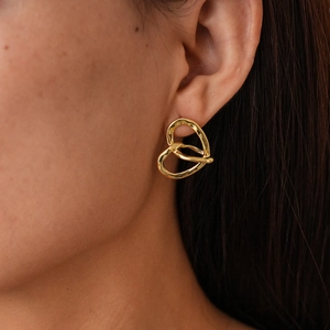 Dettaglio degli orecchini a cuore in oro 18k intrecciati indossati dal modello
