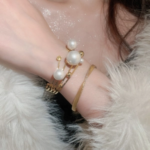 Detail of layered gold bangle with white pearls and sparkling pavé on a white fur cuff