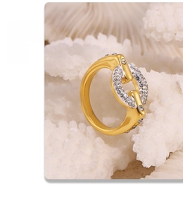 Macro detail of 18k gold plated chain link ring with shimmering crystals on white stone