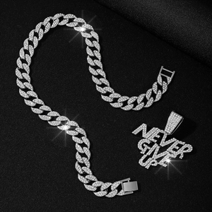 Macro shot of silver Cuban chain with diamond-encrusted NEVER GIVE UP pendant on black background