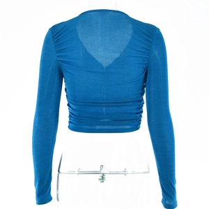 Détail du haut court bleu à manches longues montrant le design plissé du dos