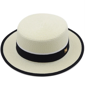 Dettaglio di cappello di paglia a cima piatta con nastro nero e accessorio in oro M