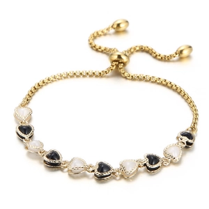 Adjustable golden copper bracelet with black and white enamel heart charms and slider clasp