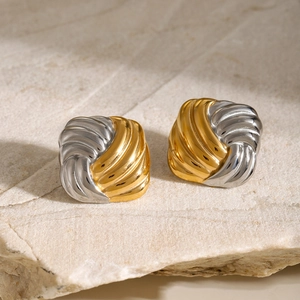 Detailed view of two-tone gold and silver knotted earrings on a natural stone base