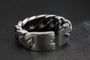 Detail of a 31mm thick polished stainless steel Cuban link bracelet for men on a dark background