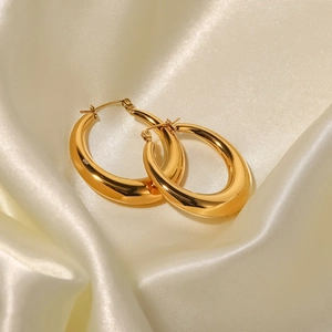 Macro shot of chunky gold hoop earrings on white silk fabric with 18K gold plating