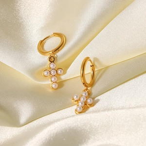 Close-up of gold titanium steel hoop earrings featuring elegant white pearl cross pendants