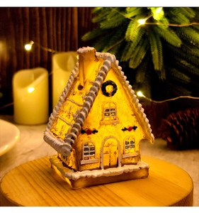 Close-up of LED glowing gingerbread house with snow texture on a wooden base