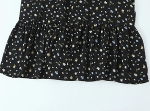 Detail view of the floral print ruffle hem on a black lightweight summer maxi dress