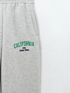 Détail du jogging gris avec broderie CALIFORNIA 1993 verte et texture en maille douce