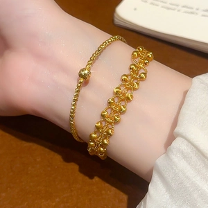 Detailed view of 24K gold-plated beaded bracelets on a wrist with elegant texture