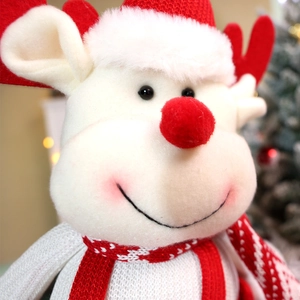 Close-up of reindeer plush toy with red antlers and festive knitting details