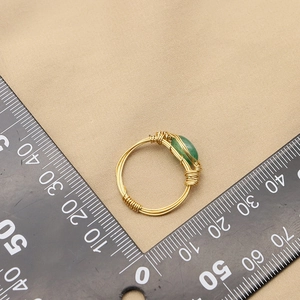 Gold wire wrapped ring with green oval gemstone shown next to a measuring ruler