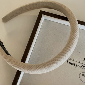 Detail of hand made beige plaid fabric headband showing fine woven texture and label