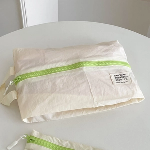Bolsa de viaje minimalista de nailon crema con cremallera verde neón y etiqueta tejida