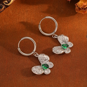 Details von silbernen Schmetterlingsohrringen mit grünen Edelsteinen und Diamanten