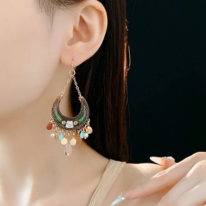 Detail of vintage bohemian crescent moon earrings with green enamel and teardrop tassel