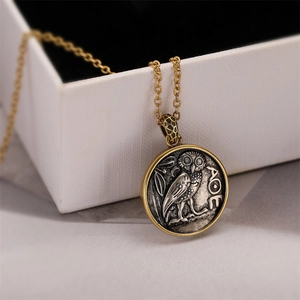 Macro shot of vintage owl coin pendant with dual-tone finish and Greek AOE engraving