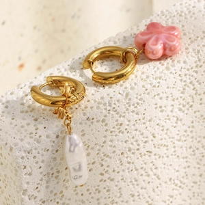 Macro shot of asymmetric 18K gold earrings with pink flower and Baroque pearl charms