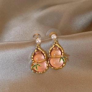 Detail of pink gourd earrings with golden bamboo leaves and white pearl on satin