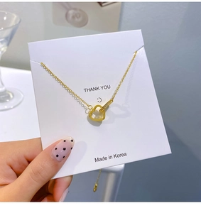 Close-up of 18k gold plated double heart pendant with diamonds on a gift card