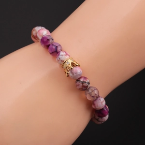 Detail of pink-purple crackle bead bracelet with a gold crown charm on model wrist