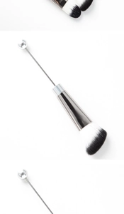 Detail of DIY beaded makeup brush with black and white bristles and silver metal handle