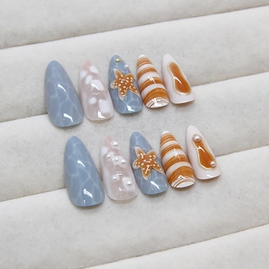 Ocean-themed stiletto press-on nails with 3D starfish, pearls, and blue wave patterns