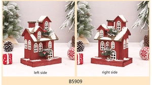 Detail view of red wooden Christmas house with artificial snow and pine cone accents