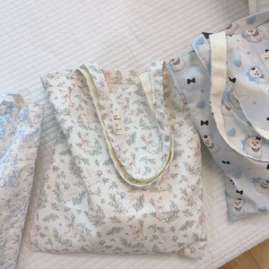 Detailansicht der blauen Blumen-, Schwanen- und Welpenmuster auf Baumwolltaschen