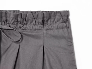 Detail of grey poplin shorts featuring drawstring elastic paperbag waist and pleat texture