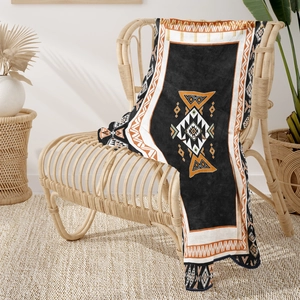 Detail of soft Aztec flannel blanket draped over a rattan chair in a warm setting