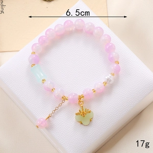 Détails d'un bracelet en perles roses avec pendentif trèfle sur une boîte blanche