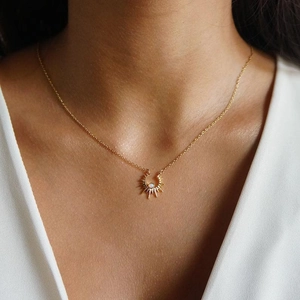 Elegant gold celestial sun pendant necklace with opal stone worn by a model