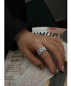 Detail of silver watch-strap style titanium steel ring on finger with lifestyle props