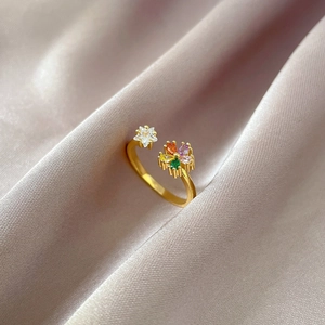 Detailed close-up of gold flower ring with colorful zircons on pink silk background