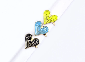 Macro detail of layered enamel heart rings with gold plating and colorful drip oil finish