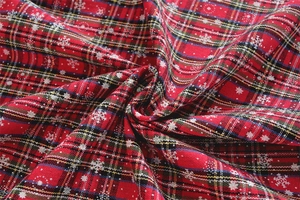 Detailed macro view of red plaid Christmas tablecloth fabric with white snowflake patterns