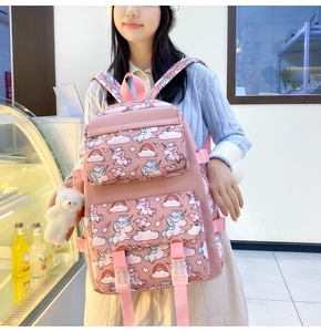 Detail of pink nylon backpack featuring cartoon unicorn patterns and a small bear plush charm