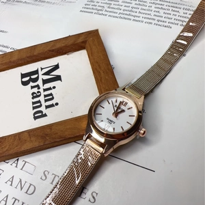 Detail view of rose gold mesh band watch on vintage paper with minimalist white dial