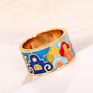 Gros plan d'une bague en émail doré avec des motifs de maisons colorées