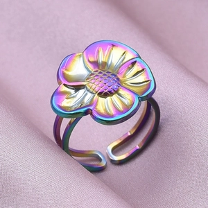 Macro shot of rainbow-plated five-petal flower ring on elegant purple silk fabric