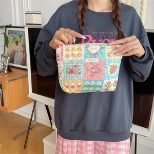 Detailed view of quilted cotton cosmetic bag with floral patchwork held by a model