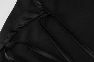 Détail du tissu en satin noir brillant avec fines bretelles et finitions de couture