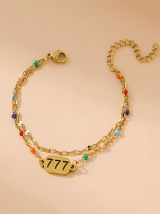 Dettaglio di bracciale a doppio strato dorato con perline colorate e ciondolo numero 777
