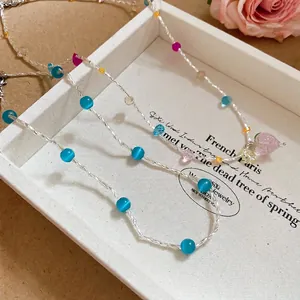 Elegante collana di perline in cristallo fragola e pietre occhio di gatto blu su vassoio
