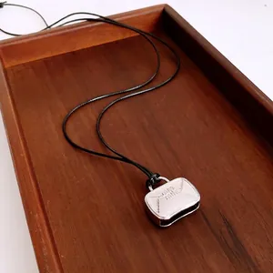 Chic silver handbag pendant necklace with black cord on an elegant wooden background